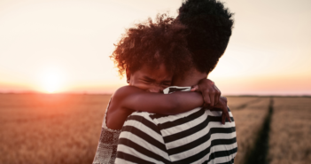 child crying on adult's shoulder