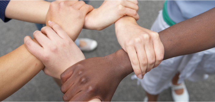 people of different races grabbing one another's wrists in unity