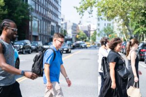 students, faculty, and university settlement staff cross the street at a crosswalk in nyc.