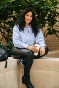 natalia arai holds a coffee cup sitting in the lincoln center campus courtyard