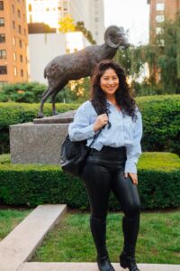 natalia arai poses in front of the ram statue in the lincoln center courtyard