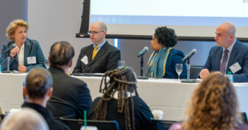 GSS Alumni Contribute Crucial Insights to Fordham Mental Health & Crime Conference McPhee and her panel sit at a long table on a stage, engaging in a discussion. The audience is visible in the foreground, while a projector screen is displayed in the background.